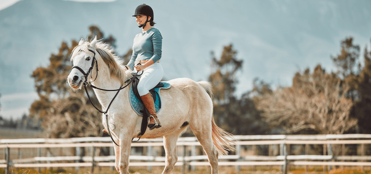 Reiterin auf Pferd vor bergiger Landschaft